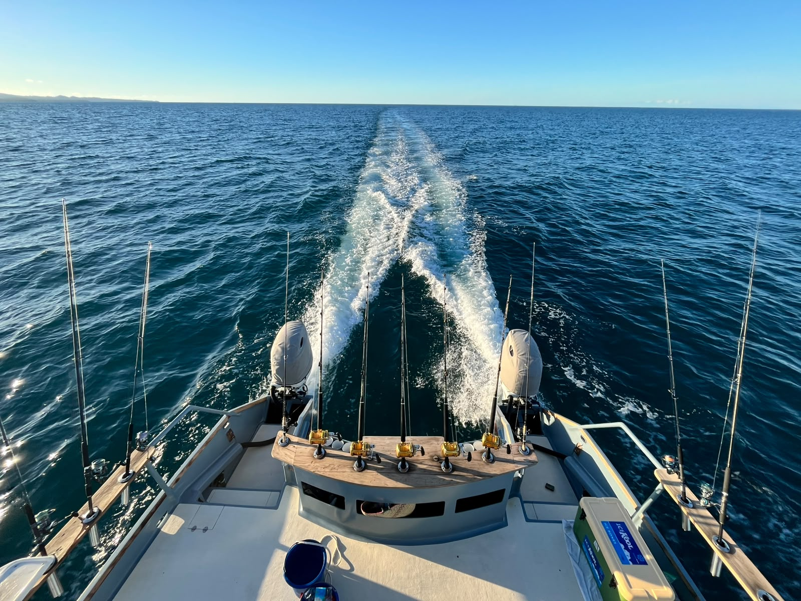 A vivid green and gold mahi-mahi leaping clear of deep blue water on the hook, spray flying